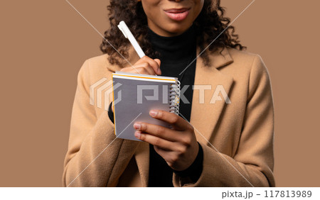 African teen girl writing notes in planner with pen. Woman thinking about future African teen girl writing notes in planner with pen. Woman thinking about future 117813989
