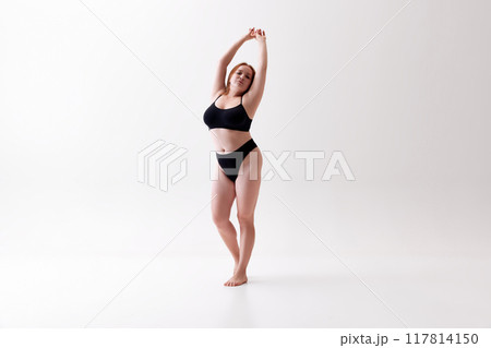 Beauty as it is. Elegant, attractive young girl with chubby body shape, confidently posing in black underwear isolated on white studio background. Beauty as it is. Elegant, attractive young girl with chubby body shape, confidently posing in black underwear isolated on white studio background. 117814150