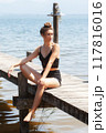 Relaxed summer atmosphere at the lake: woman in a black lace outfit on a jetty 117816016