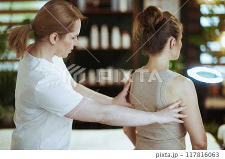 medical massage therapist checking clients back condition 117816063