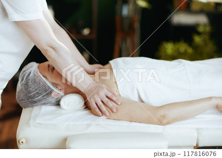 massage therapist massaging clients shoulder on massage table 117816076