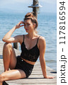 Sun-kissed: Woman in a black lace top enjoys the summer breeze by the lake 117816594