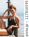 Elegance by the water: woman in a black lace outfit on a jetty by the lake 117816595