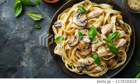Creamy fettuccine Alfredo with mushrooms and chicken on a dark rustic table 117816819