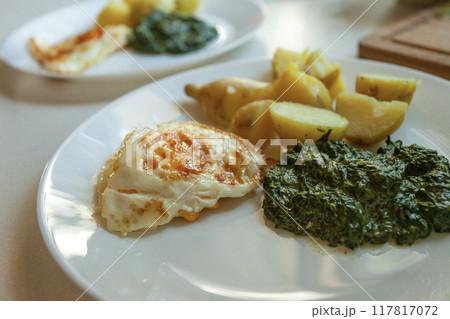 Fried egg with spinach and potatoes on a plate 117817072