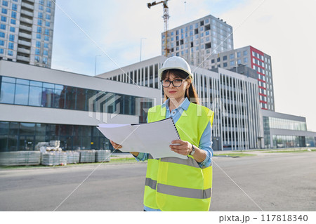 Industrial worker female builder with working documents, outdoor construction 117818340