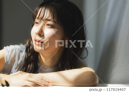 西陽の窓辺の女性 117819407