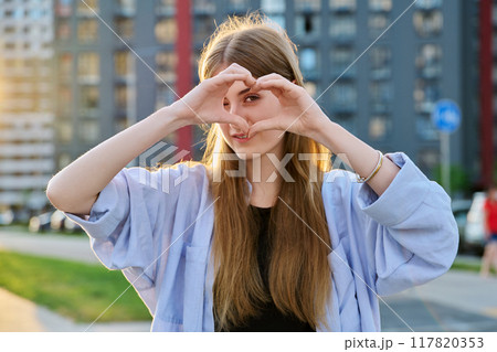 Young happy young woman showing heart with hands, city background 117820353