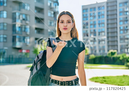 Happy young teenage female with red hair backpack making air kiss gesture Happy young teenage female with red hair backpack making air kiss gesture 117820425