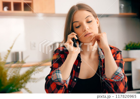 Young woman talking on the phone at home 117820965