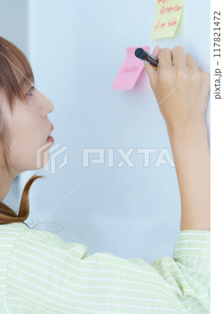 オフィスで課題を見える化する若い女性 117821472