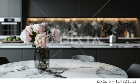 Modern kitchen with sleek black cabinetry and marble countertops. A vase with pink peonies adds a touch of elegance 117821512