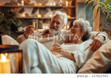 Relaxed senior couple in love enjoying serene moment among candles in spa with glasses of champagne 117822501