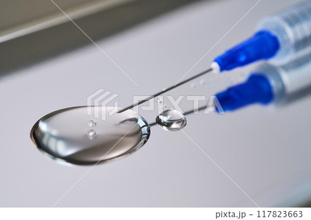 A drop of medicine flowing from a syringe with a needle. A drop of medicine flowing from a syringe with a needle. 117823663