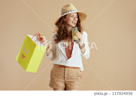 smiling stylish female in blouse and shorts against beige 117824056