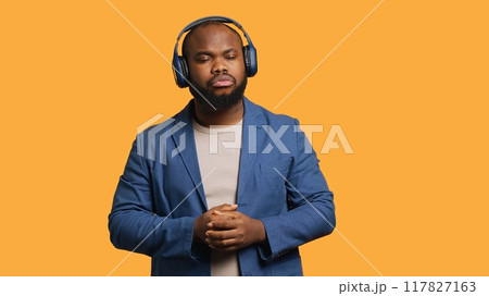 African american man feeling exhausted from overworking and lack of sleep, suffering from headache and yawning, studio background. Tired BIPOC person feeling migraine from fatigue, camera A African american man feeling exhausted from overworking and lack of sleep, suffering from headache and yawning, studio background. Tired BIPOC person feeling migraine from fatigue, camera A 117827163