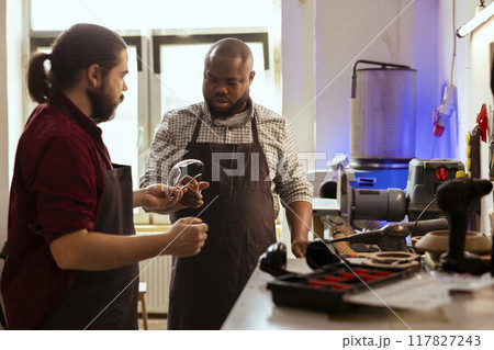 Master in woodworking shop giving BIPOC employee protection glasses before assembling furniture. Manufacturer preparing safety gear for african american apprentice before starting work Master in woodworking shop giving BIPOC employee protection glasses before assembling furniture. Manufacturer preparing safety gear for african american apprentice before starting work 117827243