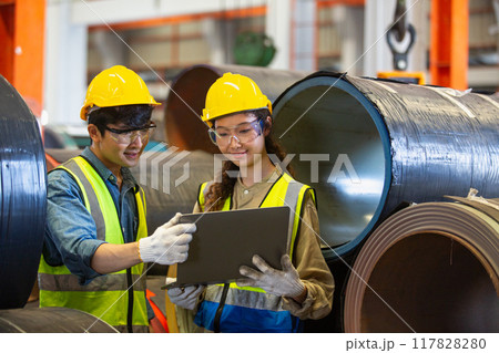 female and male wearing safety uniform worker use laptop checking quality product metal female and male wearing safety uniform worker use laptop checking quality product metal 117828280