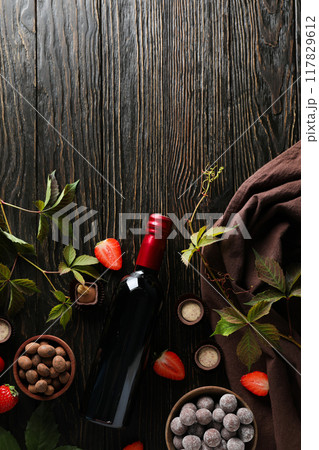 A bottle of wine on a dark, wooden table with flowers. A bottle of wine on a dark, wooden table with flowers. 117829612
