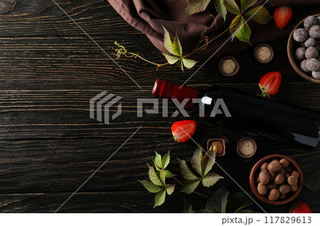 A bottle of wine on a dark, wooden table with flowers. A bottle of wine on a dark, wooden table with flowers. 117829613