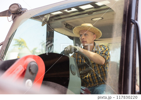 Portrait of focused male worker driving tractor 117830220
