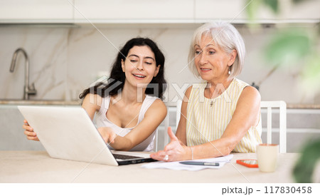 Elderly woman discussing deal with saleswoman in kitchen Elderly woman discussing deal with saleswoman in kitchen 117830458