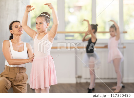 Woman teacher corrects movement of girl dancer 117830459