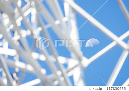 白い鉄塔の間から見える半月 117830486