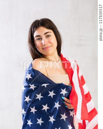 Happy young woman with flag of the USA against unicoloured background 117830517