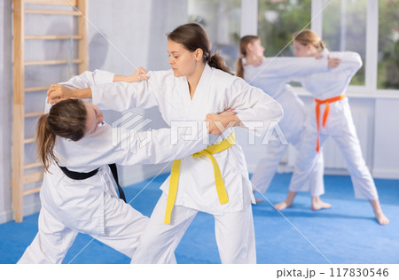 Female athletes in pair conduct training battle in oriental fighting technique Female athletes in pair conduct training battle in oriental fighting technique 117830546
