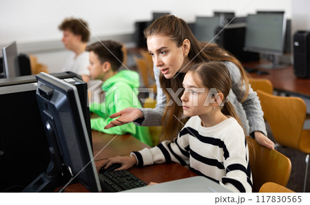 Female teacher helping teen schoolgirl studying in computer lab Female teacher helping teen schoolgirl studying in computer lab 117830565