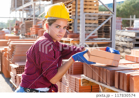 Portrait of a young girl worker laying bricks in a warehouse Portrait of a young girl worker laying bricks in a warehouse 117830574