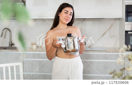 Young woman posing with saucepan in kitchen at home Young woman posing with saucepan in kitchen at home 117830606