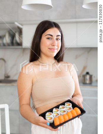 Young woman posing with set of rolls in kitchen 117830830
