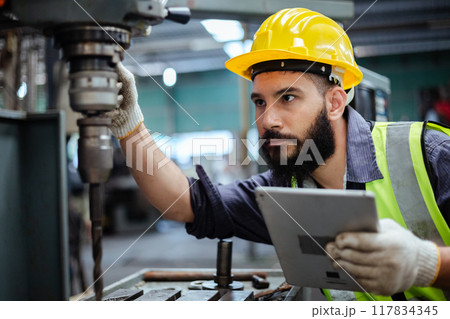Man technician worker using tablet control setting up checking operating machinery of lathe metal Man technician worker using tablet control setting up checking operating machinery of lathe metal 117834345