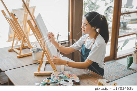 Art student drawing with watercolor painting on canvas doing some art projects on studio workshop Art student drawing with watercolor painting on canvas doing some art projects on studio workshop 117834639