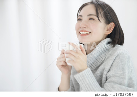 コーヒーを飲むセーターを着た若い女性 117837597