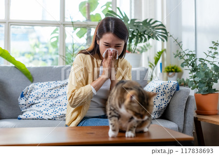 young woman has sneezing and burning nose due to an allergic reaction to owning cat. young woman has sneezing and burning nose due to an allergic reaction to owning cat. 117838693