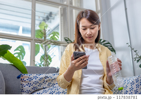 Female use smartphone to check plastic bottle trash for into waste sorting bin Female use smartphone to check plastic bottle trash for into waste sorting bin 117838781