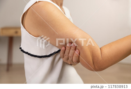 Middle aged woman worry squeezing excess fat on upper arms. 117838913