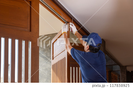 Handyman fixing bifold doors sticking or not sliding properly. 117838925