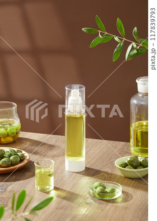 An empty bottle displayed on wooden table with fresh olives on bowls, olive oil and green leaves decorated on brown background. Mockup bottle unlabeled for design An empty bottle displayed on wooden table with fresh olives on bowls, olive oil and green leaves decorated on brown background. Mockup bottle unlabeled for design 117839793