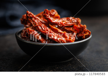 Sun dried red tomatoes in bowl on black table. Sun dried red tomatoes in bowl on black table. 117840583