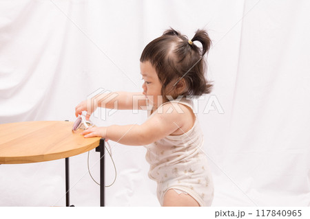 【テーブルでつかまり立ちをするツインテールの赤ちゃん】 117840965