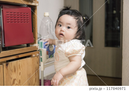 【キッチンでつかまり立ちをするツインテールの赤ちゃん】 117840971