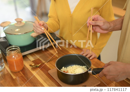 Close up shot of young couple sharing a bowl of instant noodles enjoying a casual meal in kitchen Close up shot of young couple sharing a bowl of instant noodles enjoying a casual meal in kitchen 117841117