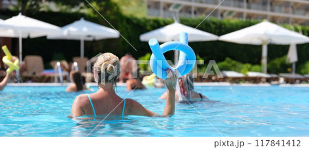 Woman in the pool doing exercises in aquafitness, back view Woman in the pool doing exercises in aquafitness, back view 117841412
