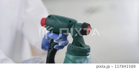 Spray gun in the hands of a builder, close-up Spray gun in the hands of a builder, close-up 117841589