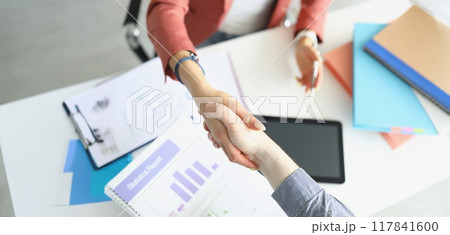 A woman in the office shakes hands with a man 117841600
