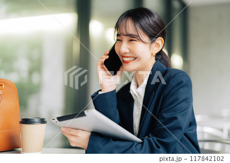 カフェのテラスで電話をする女性 117842102